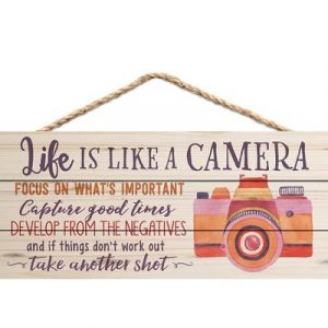 Our Life Is Like A Camera Hanging Sign features the quote "Life is like a camera: Focus on what's important, capture good times, develop from the negatives, and if things don't work out, take another shot."